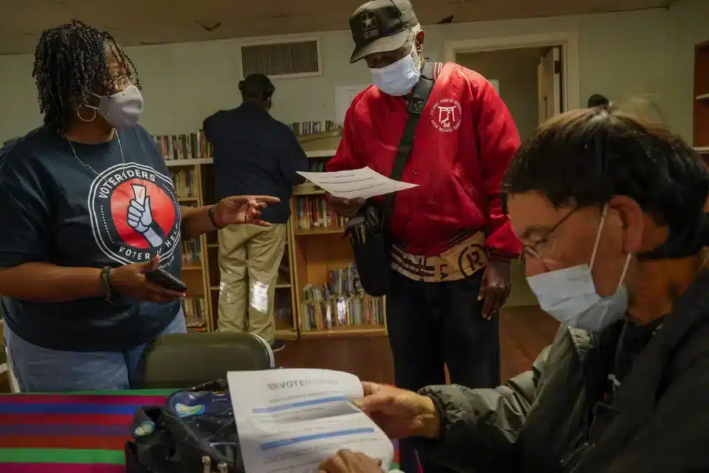 Rev. Monica Spencer Hands Out VoteRider Vouchers To Two Applicants So They Dont Have To Pay For ID Cards